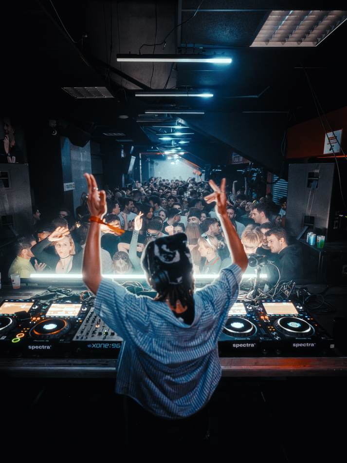 Le DJ face au public dans la coursive du Standard, bras levés